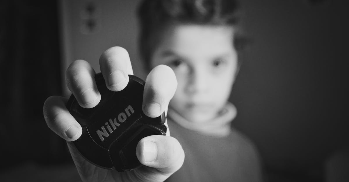 What's with dark "shining" in old black and white TV? - Selective Focus Photography of Boy Holding Nikon Lens Cover