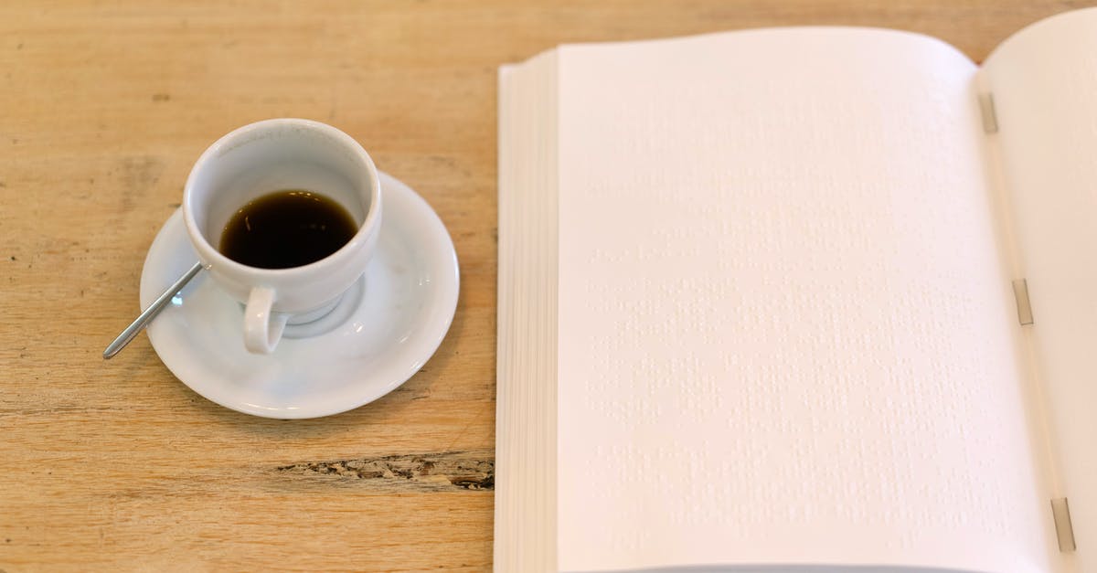 What's written on Q's cup in Skyfall? - White Ceramic Coffee Cup and Saucer Near a Journal Book