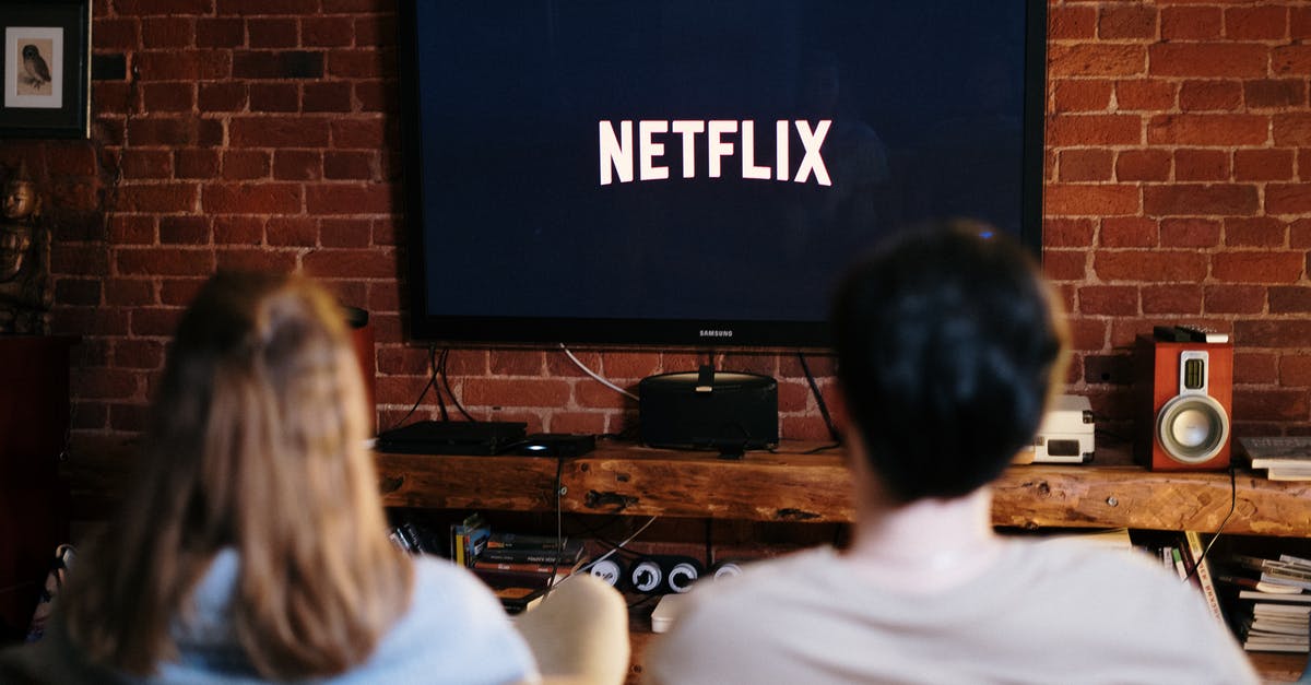 What are the awards for which Netflix original movies are eligible? - Man and Woman Sitting on a Couch in Front of a Television