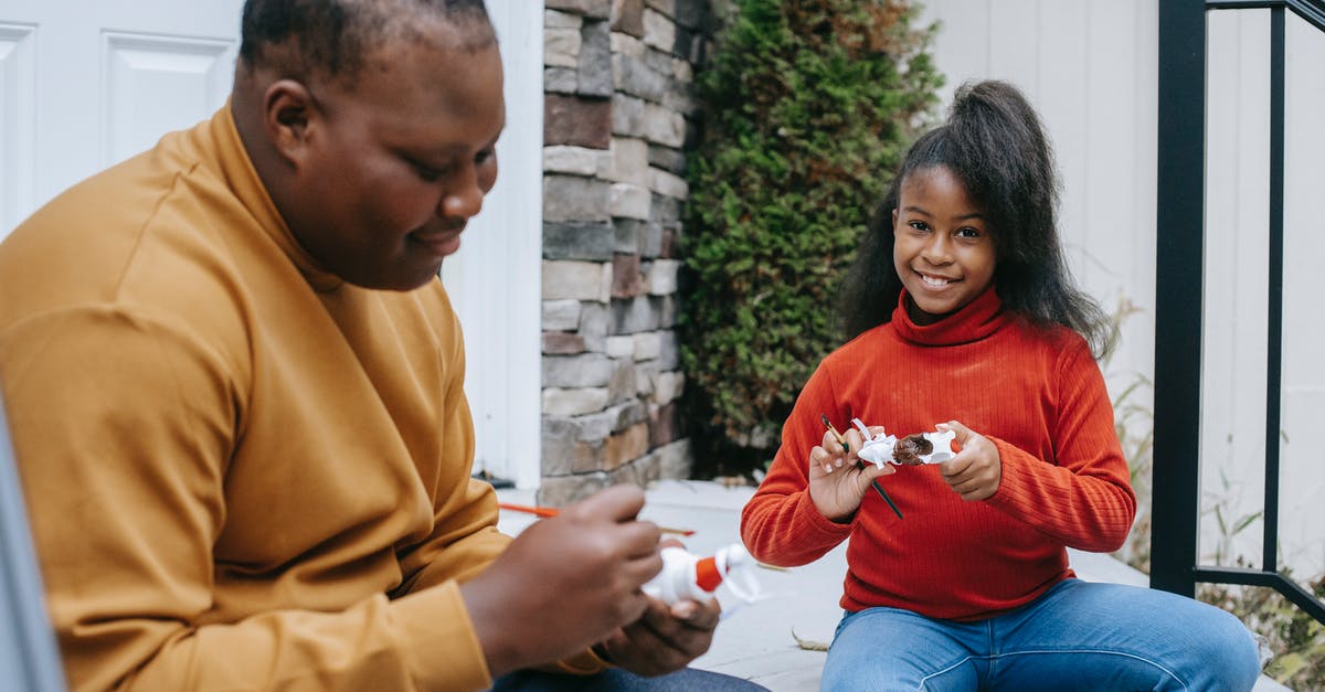 What are the Ghost of Christmas Present's Brothers? - Cheerful African American brother and sister sitting on porch and drawing on Christmas tree toys while preparing for holiday celebration