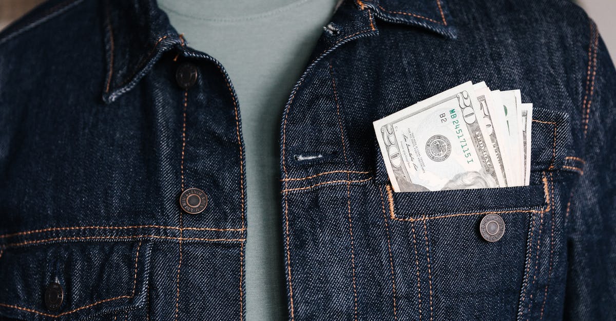 What are the key differences in the recent American remake? - Crop unrecognizable male in casual outfit standing with different nominal pars of dollar banknotes in pocket of jeans jacket