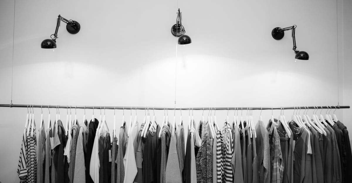 What are those items hanging behind the shop keeper? [closed] - Grayscale Photography of Assorted Shirts Hanged on Clothes Rack