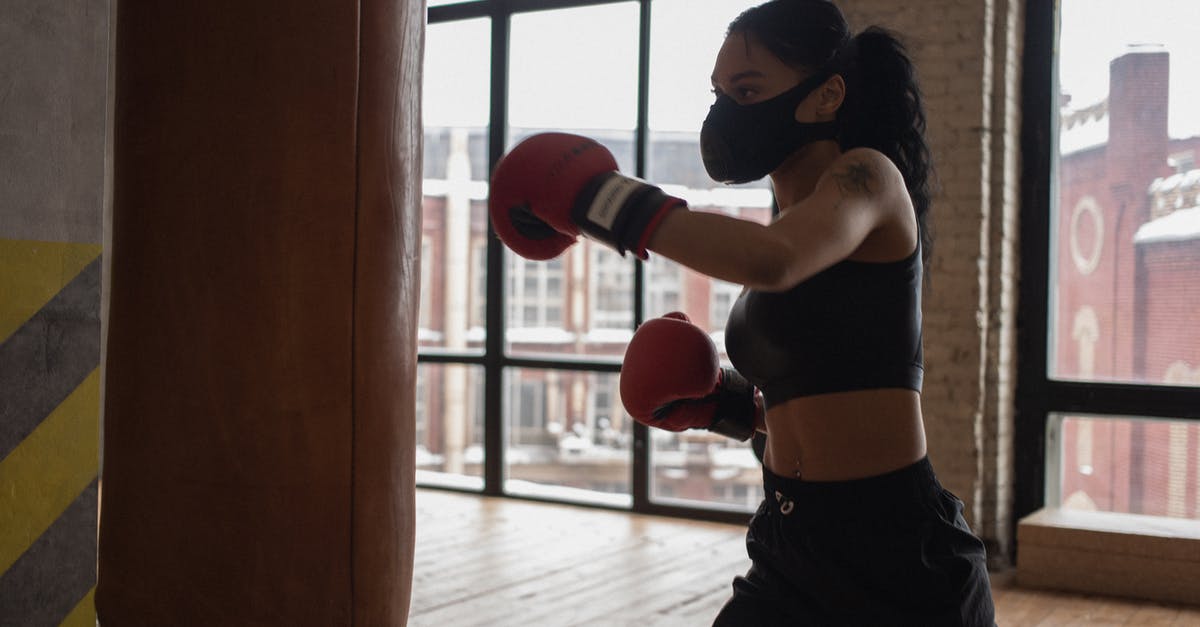 What caused Sylvester Stallone to get into a fight with Richard Gere? - Determined African American female fighter in cloth face mask and gloves during workout against boxing bag in gym