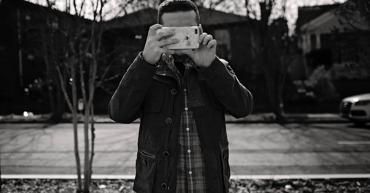 What city is used for cityscape shots in The Flash? - Black and white shot of faceless man in casual clothes standing on pavement and taking photo on smartphone