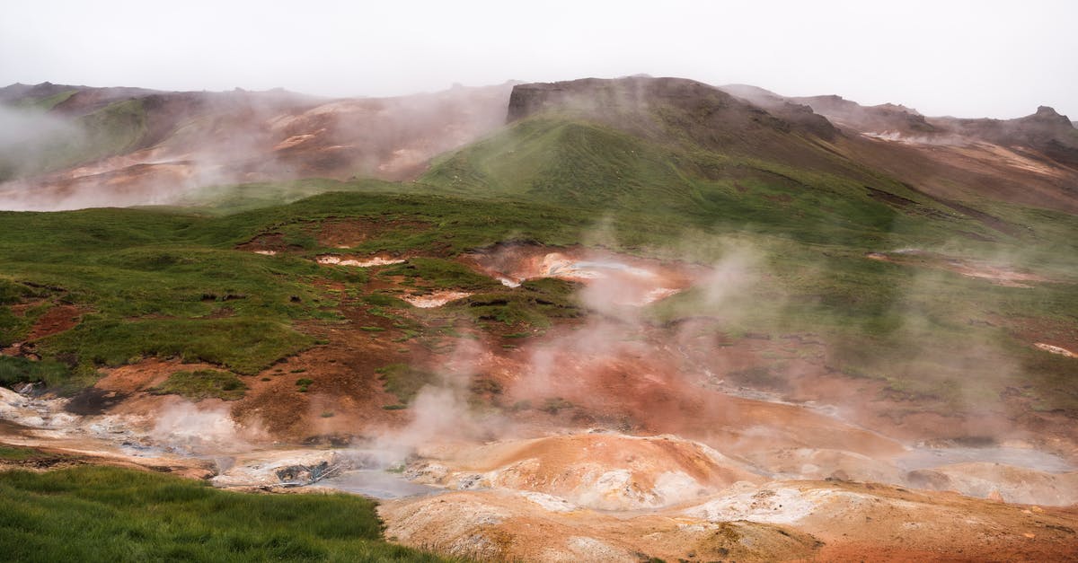 What country does No Escape take place in? - Hilled country with geysers blowing steam off among grass area against volcanic mountains in cloudy day
