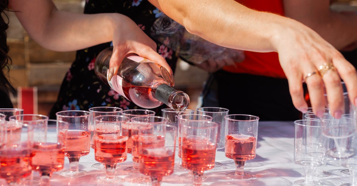 What did Amy drink out of the red plastic cup in the bathroom? - Crop anonymous female pouring red alcohol into transparent cups for guests at festive event