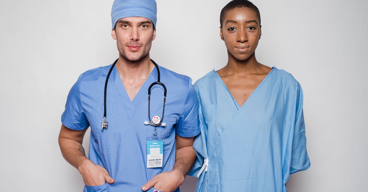 What did Maxine mean when she told Jill the Doctor would be coming back? - Positive male doctor in blue uniform with hands in pockets smiling and looking at camera while standing near nurse holding hands behind back in hospital