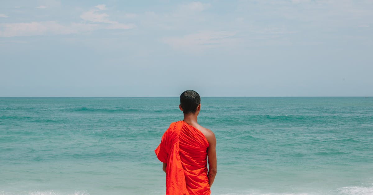What did Mr. Monk major in? - Unrecognizable Asian male monk in traditional orange robe on seashore