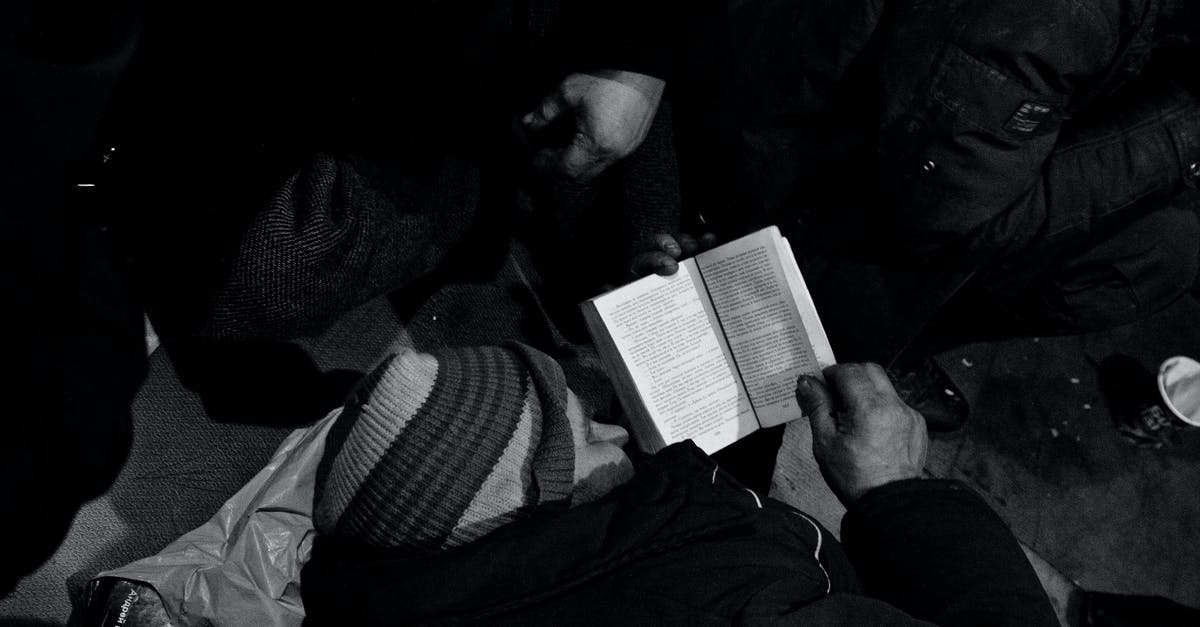 What did the aliens need help for? - Black and white of homeless man lying on floor and reading book in night shelter for homeless
