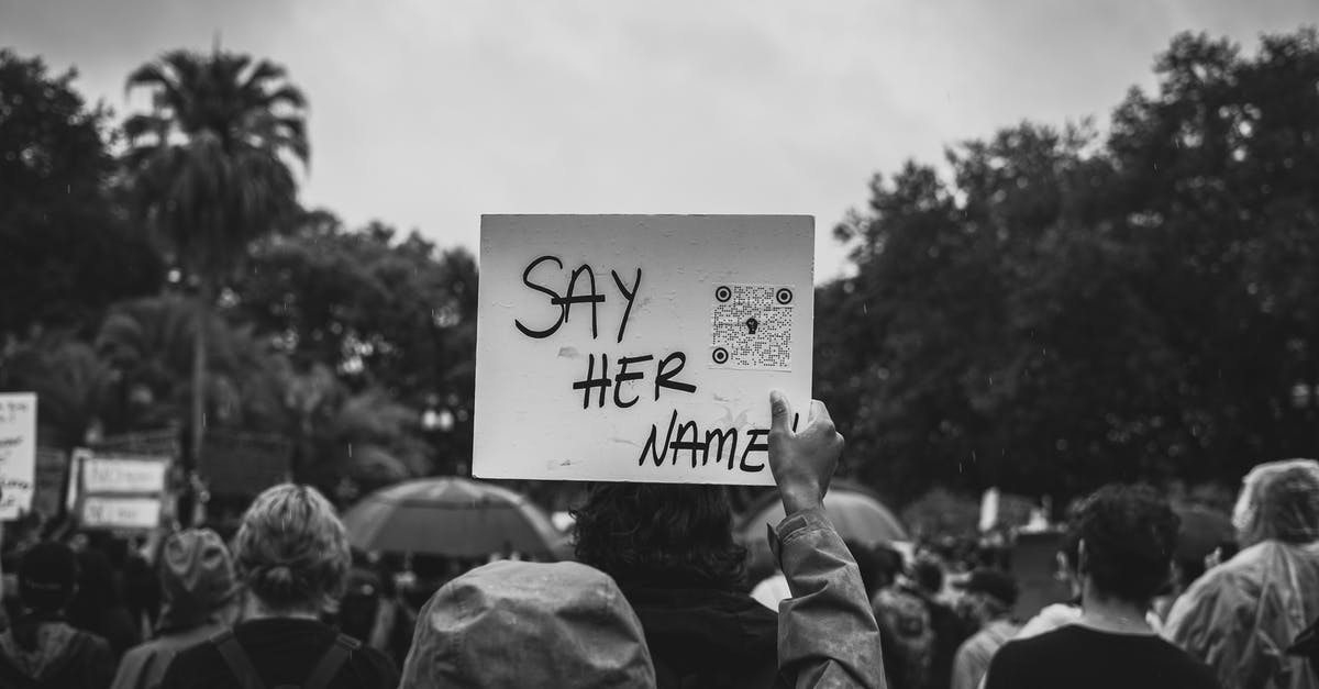 What did the sign say? - Grayscale Photo of People Holding Banner
