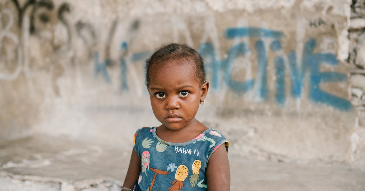 What did they need Hyde for? - Frowning African American girl near weathered concrete building with vandal graffiti and broken wall in poor district