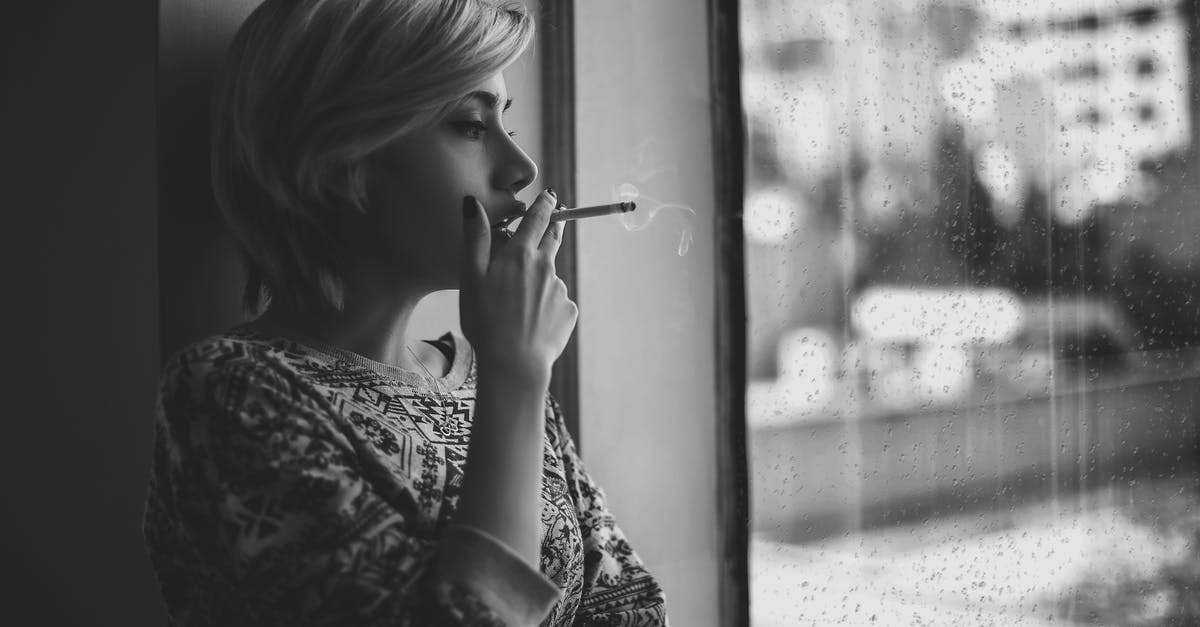 What do actors actually inhale when their characters snort cocaine or smoke crack? - Black and white depressed female with short haircut smoking cigarette and looking out window at rainy city