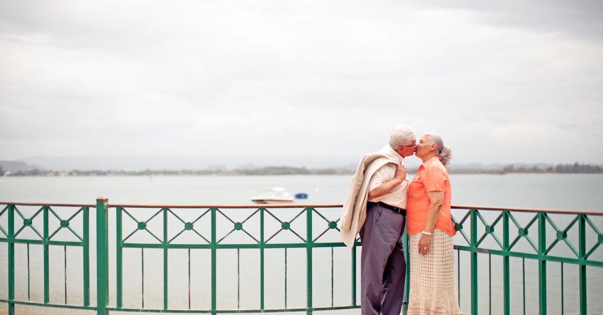 What do the colours in the different areas in The Cook, The Thief, His Wife & Her Lover signify? - Side view full body romantic senior couple wearing trendy outfits standing on waterfront promenade and kissing gently on overcast weather