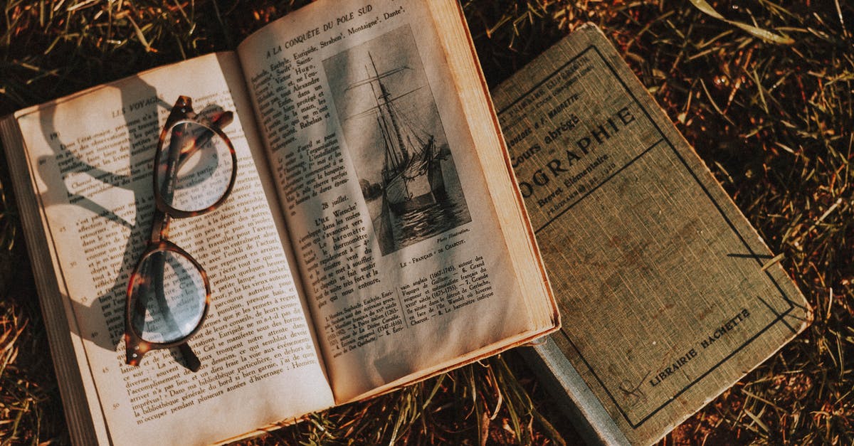 What does Book of Shadows stands for in title of movie Book of Shadows: Blair Witch 2? - From above of old textbooks with illustration and eyewear on open page on dry grass in sunlight