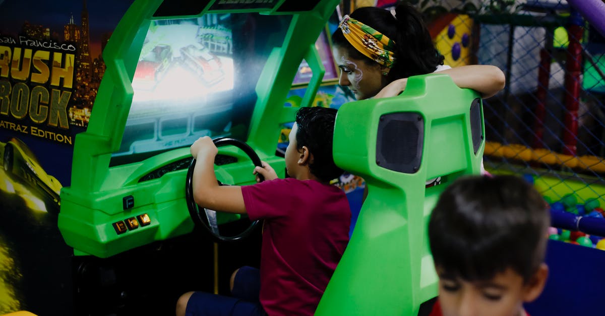 What does Mr Bean have against the three-wheeled car? - Anonymous boy playing car racing simulator near mother and sibling
