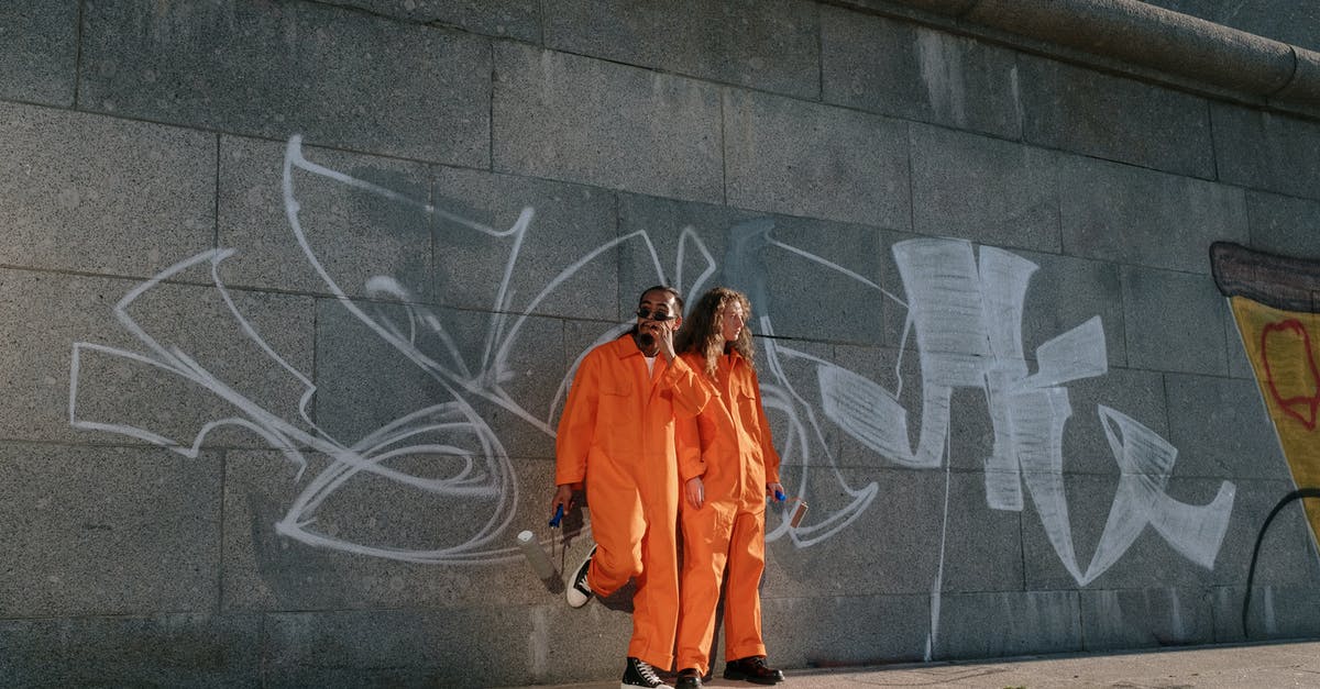 What does the graffiti wall of The Magicians mean? - Woman in Orange Coat Standing Beside Wall