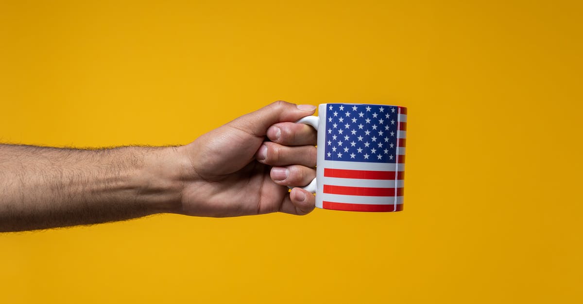 What does the missing symbol on Quaid's arm symbolize? - Person Holding a Mug with a US Flag Design