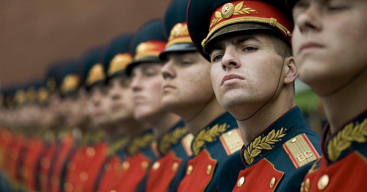 What does the Russian soldier say to Sarah Ross while she is pretending to be a guard in the Kremlin? - Men in Black and Red Cade Hats and Military Uniform