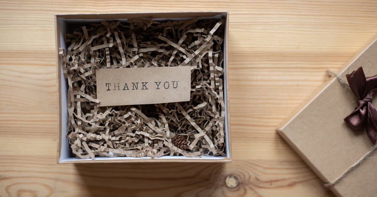 What does the wooden box scene signify? - Top view of opened carton present box with small postcard with Thank You inscription and paper stuffing on wooden table