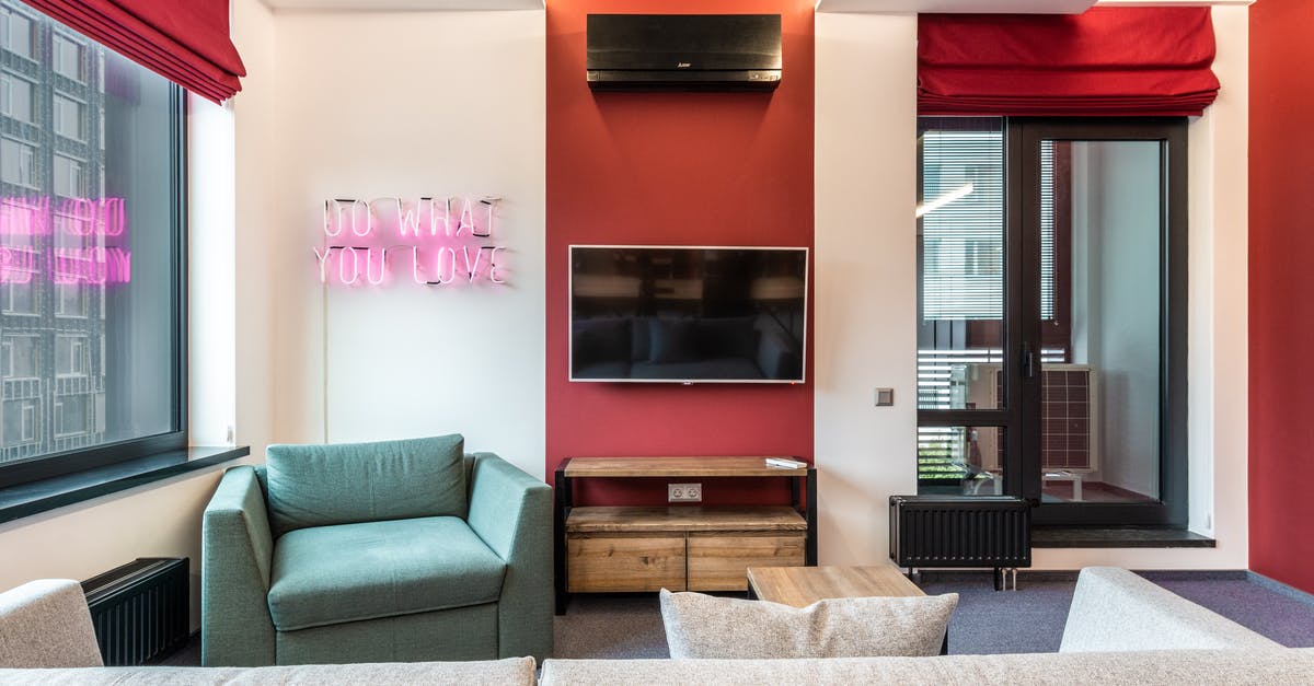 What does this Oompa Loompa whisper to Wonka in the T.V. Room? - Interior of modern office lounge zone with sofa and armchair with table near window next to TV on wall and neon signboard with text do what you love near door