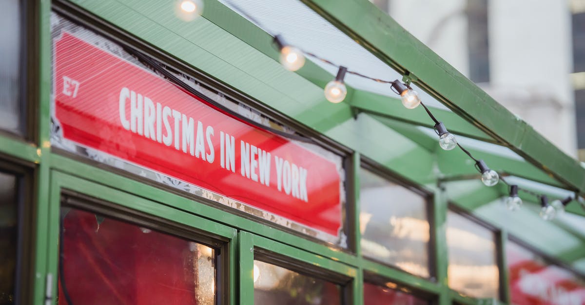 What event led to Eddie Brock leaving New York City - Low angle red signboard with Christmas In New York inscription hanging on glass showcase of shop on city street