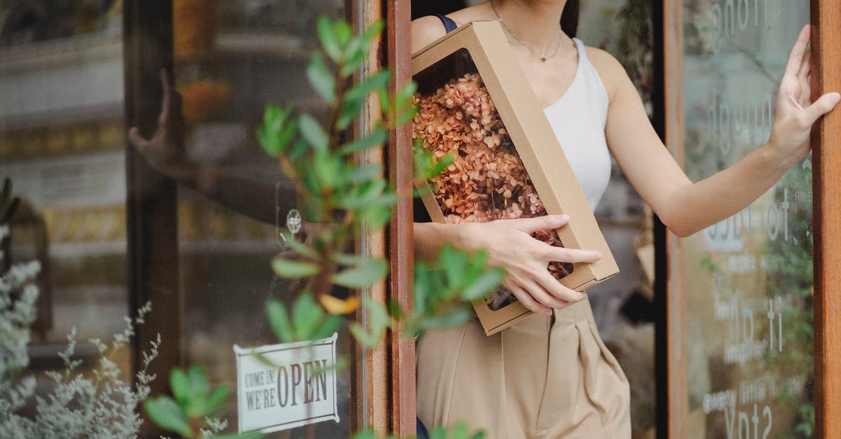 What evidence is there for each side of the debate over the authenticity of "Exit Through The Gift Shop"? - Crop glad woman with dried flowers box leaving floristry store