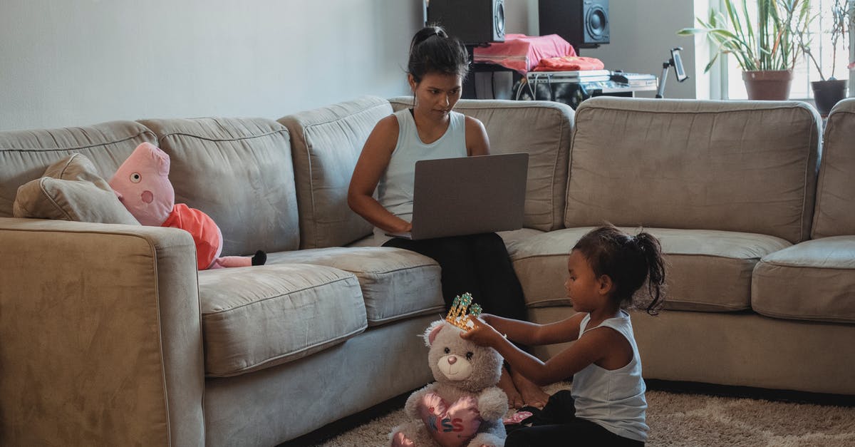 What happened to Ralph's game while he was inside the Internet? - Mother working on computer while sitting on couch and daughter playing with toys on floor in living room