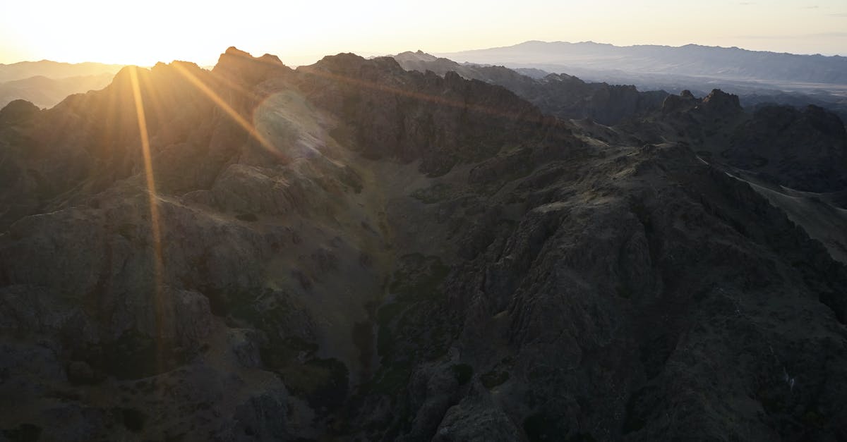 What happened to the last of the sins in Se7en? - Majestic drone view of mountain range almost plunged into darkness touched by last sunbeam of setting sun causing lens flare