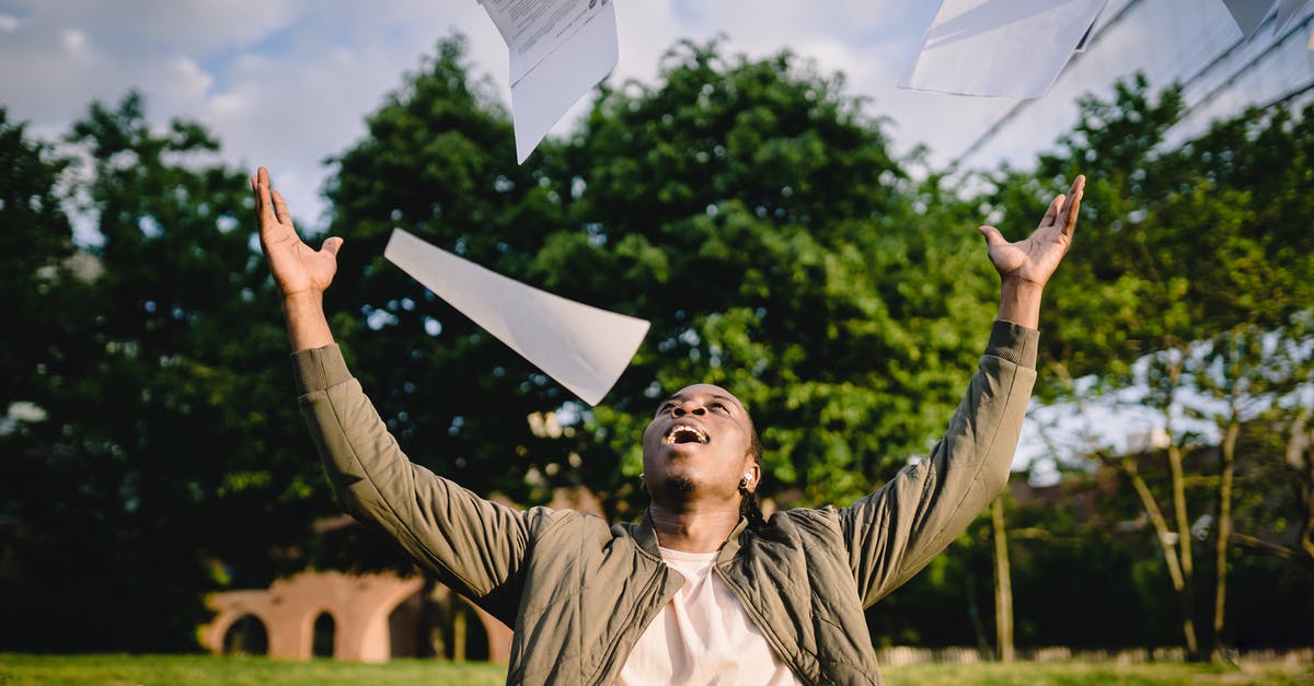 What happens at the end of "How to Rob a Bank (and 10 tips to get away with it)" - Cheerful young African American male student in casual clothes throwing college papers up in air while having fun in green park after end of exams
