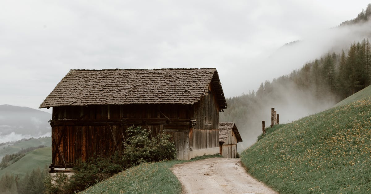 What happens in the house in episode 10 season 2? - Old rural brown houses with triangle roof on mountain slope covered with grass and yellow flowers next to road and forest on mountain in fog