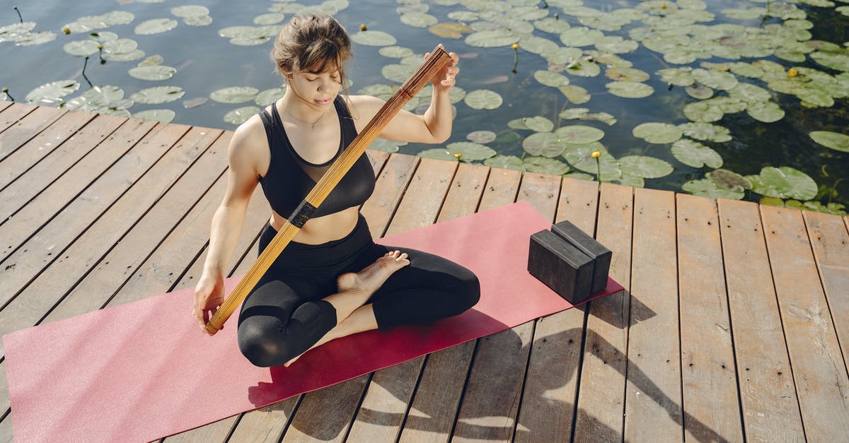 What is Ben Affleck's character doing massaging his leg with a wooden stick - Woman Exercising Yoga on Mat by a Pond
