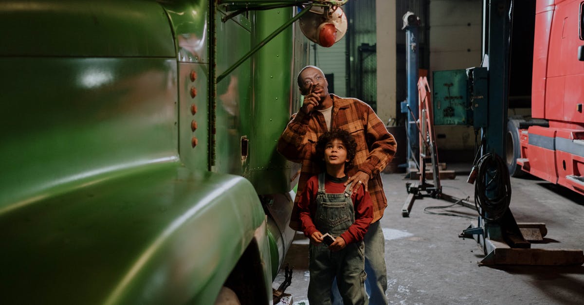 What is the context of the garages in The Americans? - Father and Son Standing Beside a Truck
