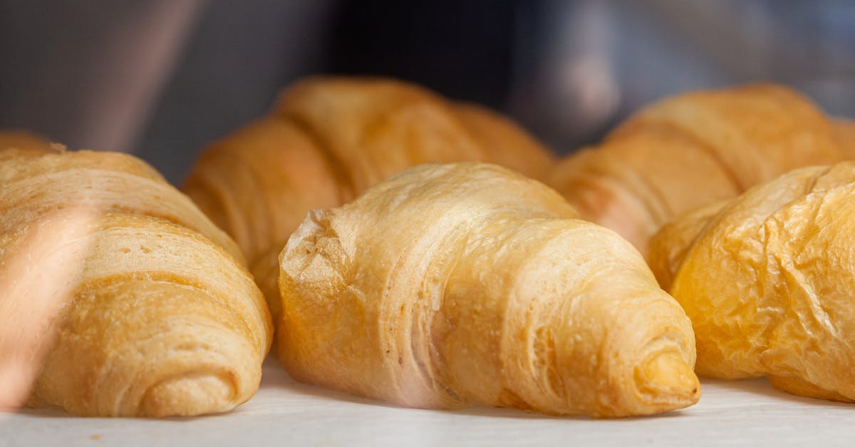What is the English translation of the French dialogue in "Croissant de Triomphe"? - Delicious fresh croissants with golden crust placed on white surface in light cafe