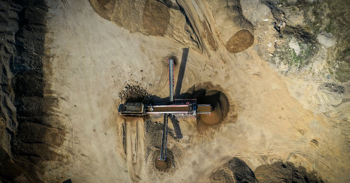 What is the geographic location of the pit Bruce Wayne is imprisoned in by Bane? - Aerial view of old sand mining construction build on sandy hilly terrain in daylight