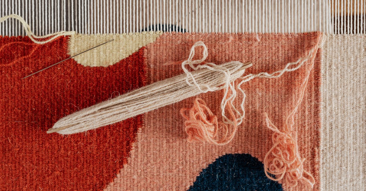 What is the importance of the souvenir from Lagos, Nigeria? - From above of shuttle and needle placed on part of handmade carpet with circle pattern on loom frame during weaving process