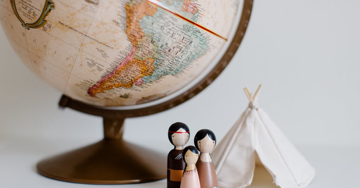 What is the importance of the souvenir from Lagos, Nigeria? - From above of miniature toys tipi house and American Indian family placed near vintage globe against gray background at daytime