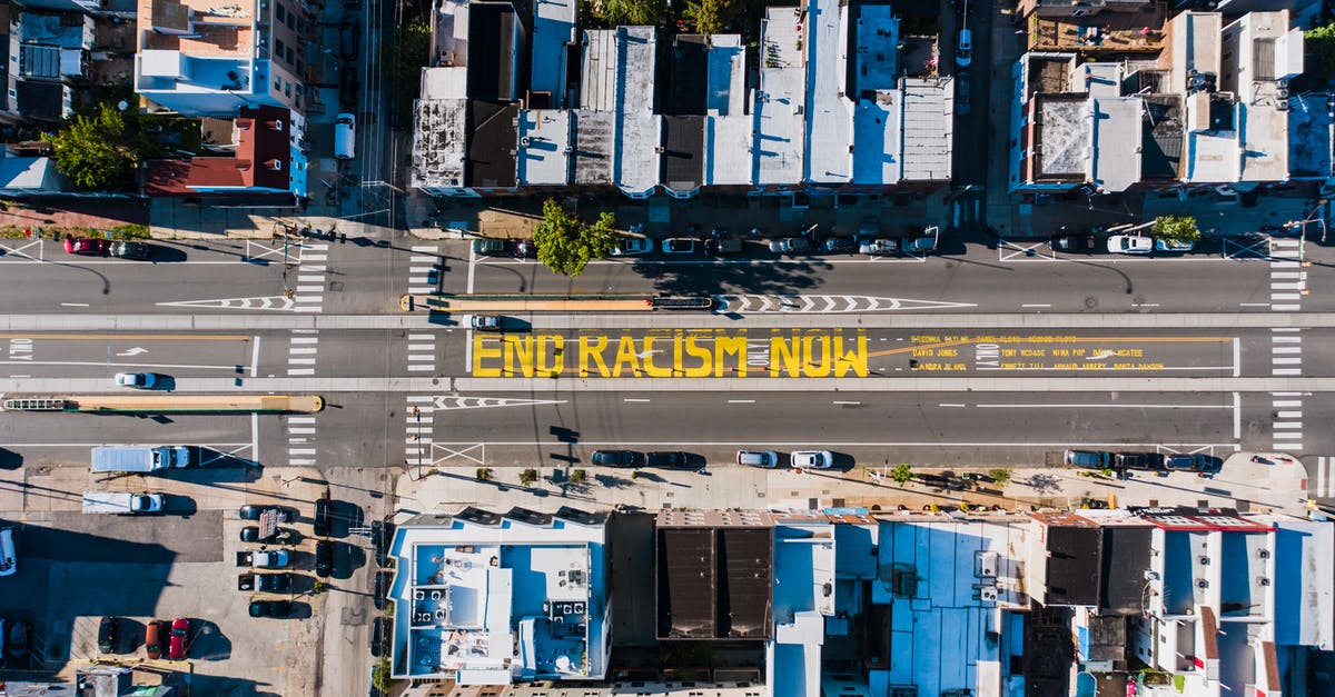 What is the meaning of the line at the end of Chinatown? - Overhead view of asphalt roadway with vehicles between building roofs and colorful title about racism