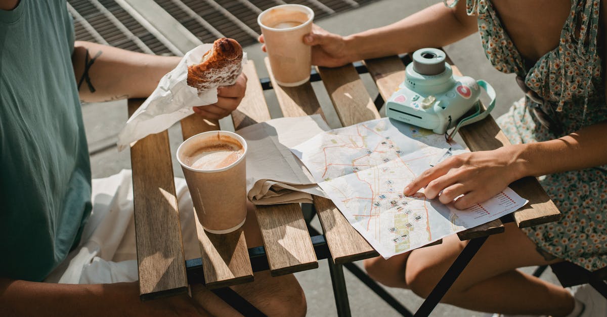 What is the point of the girlfriend scenes? - From above of crop anonymous couple searching route in map while having coffee and croissant