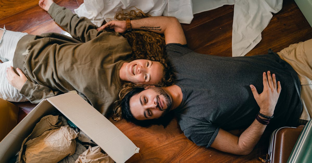 What is the relationship between "multi-camera" and laugh tracks? - From above of young smiling diverse couple in casual clothing relaxing on floor near carton boxes while unpacking belongings in new contemporary apartment