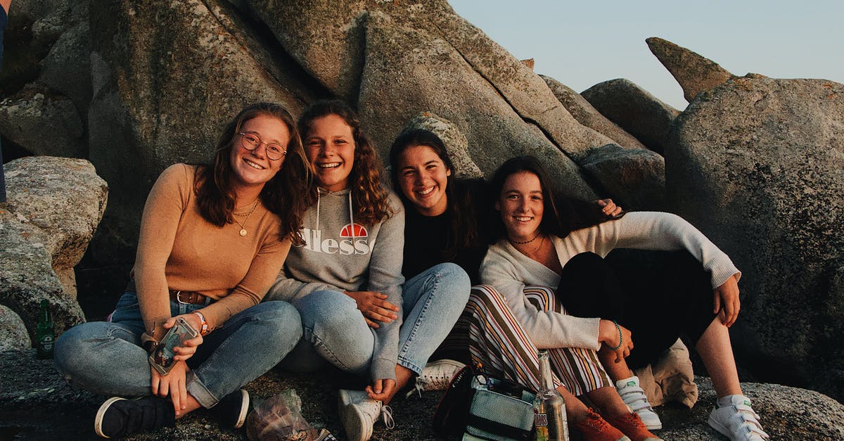 What is the relationship between "multi-camera" and laugh tracks? - Group of cheerful young female friends in casual clothes laughing and looking at camera while sitting with drinks and snacks on rocky seashore and having fun during travel together