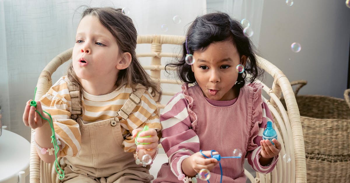 What is the significance of the stick with the wolf face? - Carefree multiracial girls blowing soap bubbles in armchair at home