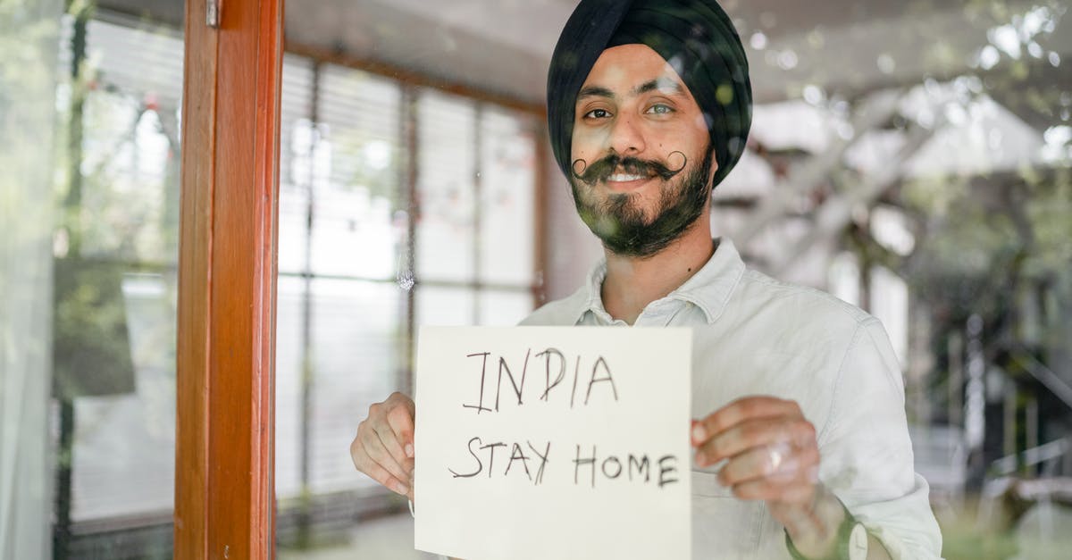 What is the significance of the title Peaceful Warrior - Indian man showing INDIA STAY HOME inscription through glass