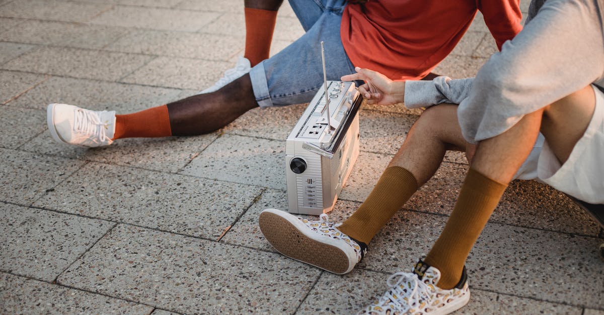 What is the song played in the radio station just before the semi-finals? [closed] - Crop multiethnic friends sitting on tiled ground and listening to music on vintage portable sound system including radio and cassette player