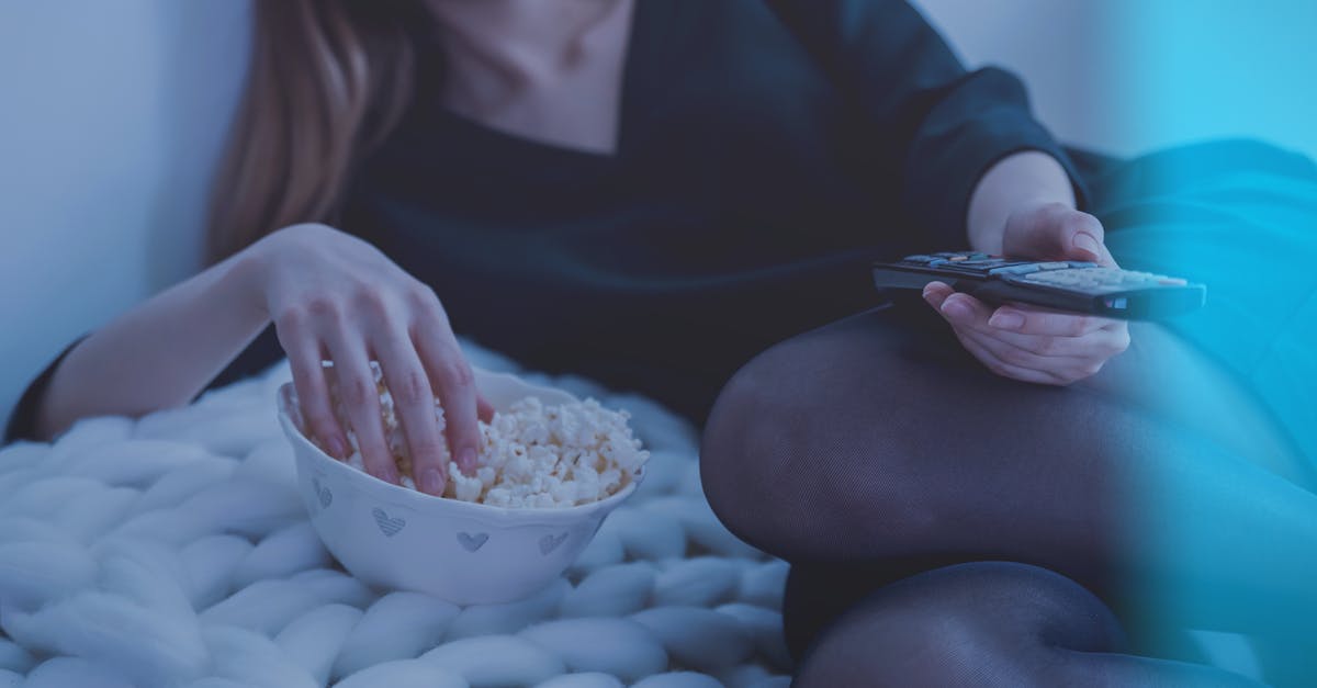 What is the supervisor girl doing in TV show 3%? - Woman in White Bed Holding Remote Control While Eating Popcorn