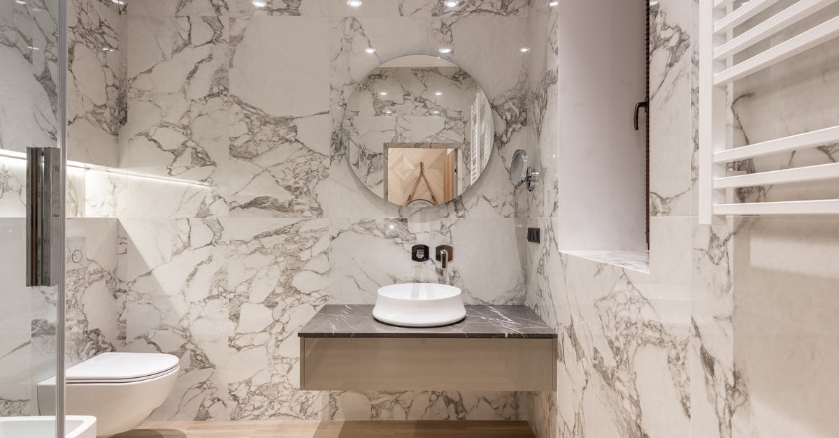 What is the whistling in the restroom about in "My Name is Nobody"? - Interior of modern bathroom with round mirror hanging on marble wall and white ceramic sink and toilet bowl