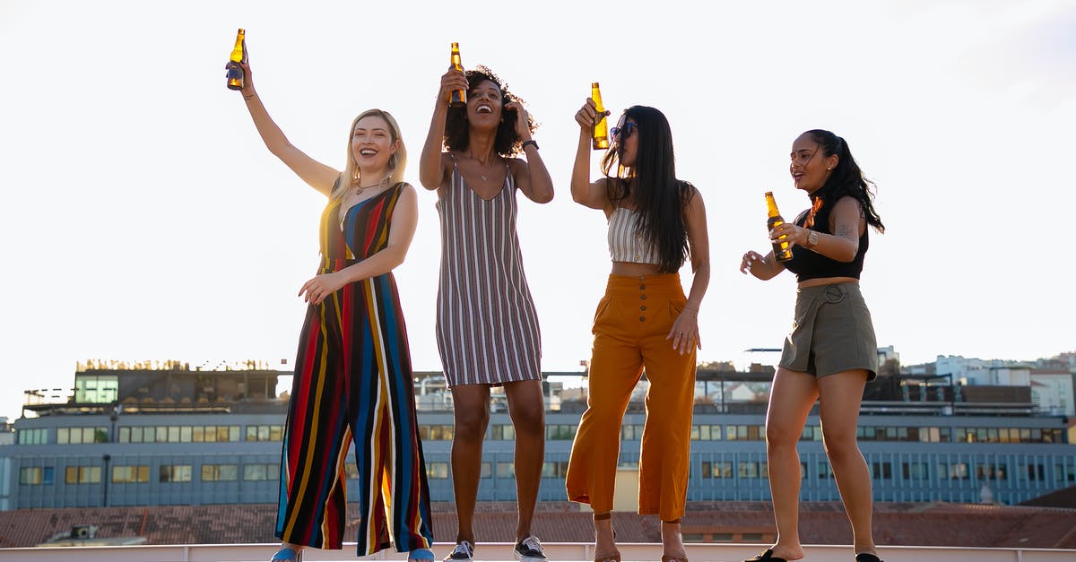 What is this building that seems to have a giant torch on the roof? [closed] - Full body of happy young diverse girlfriends dancing and drinking beer while having fun together during open air party on building rooftop