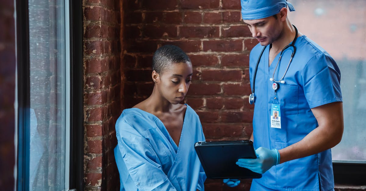 What is this importance of the mist that appears in the hospital corridor? - Thoughtful doctor in uniform and gloves showing diagnosis to African American female patient with short hair in blue medical robe in hallway of hospital in daytime