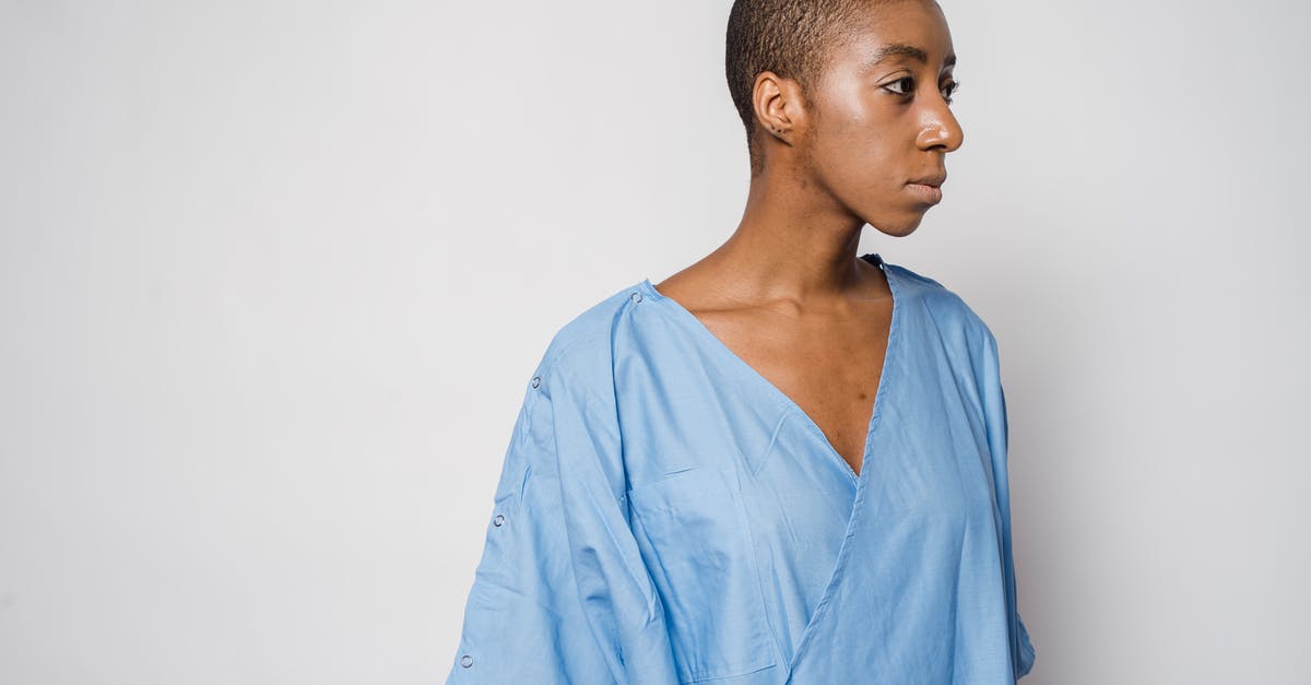 What is this importance of the mist that appears in the hospital corridor? - Pensive androgynous African American female patient with short dark hair in medical robe standing against light wall and looking away