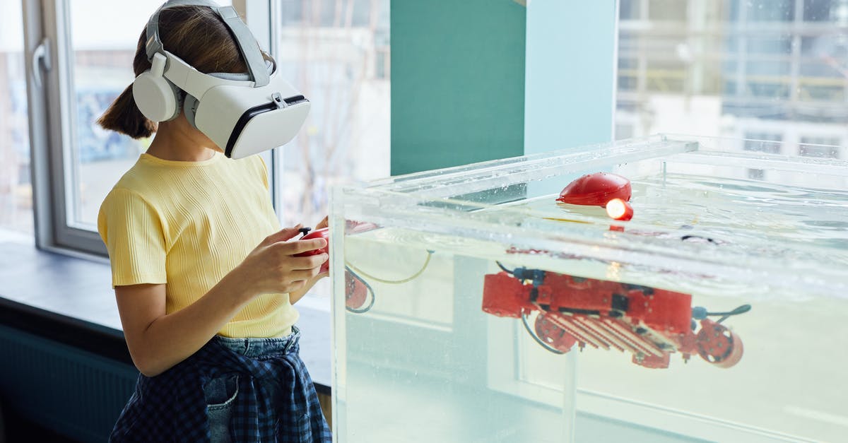 What kind of heat vision goggles? - Side view of little girl wearing VR goggles and exploring new robot with controllers in light room