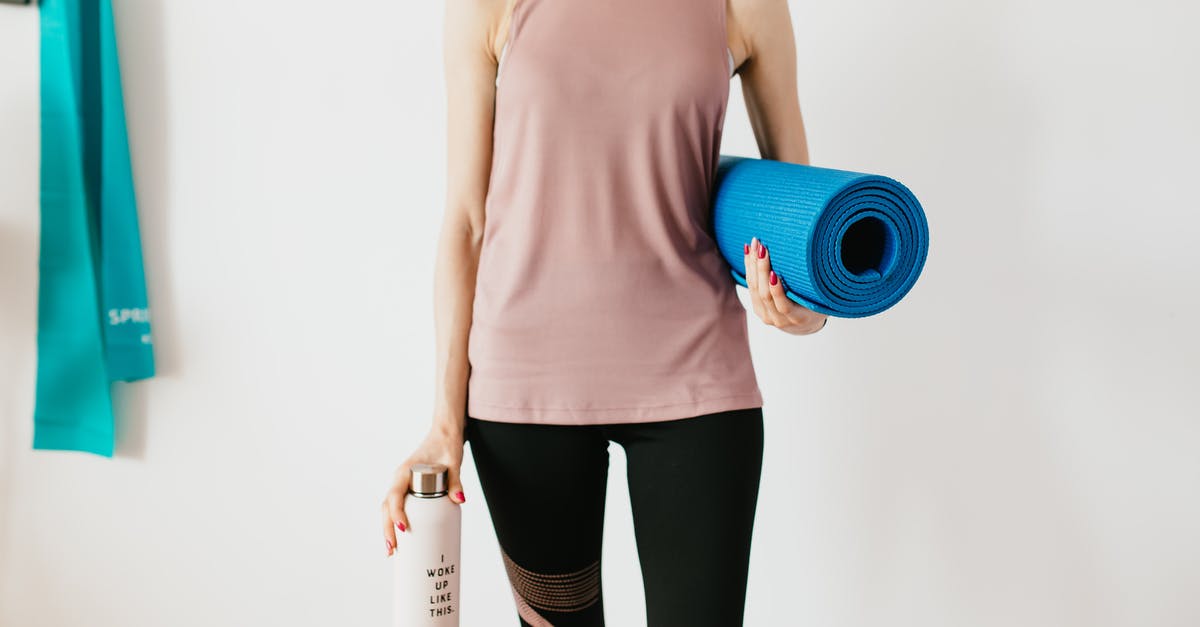 What motivated Mr. Smith to carry on? - Faceless slim female athlete in sportswear standing with blue fitness mat and water bottle while preparing for indoors workout